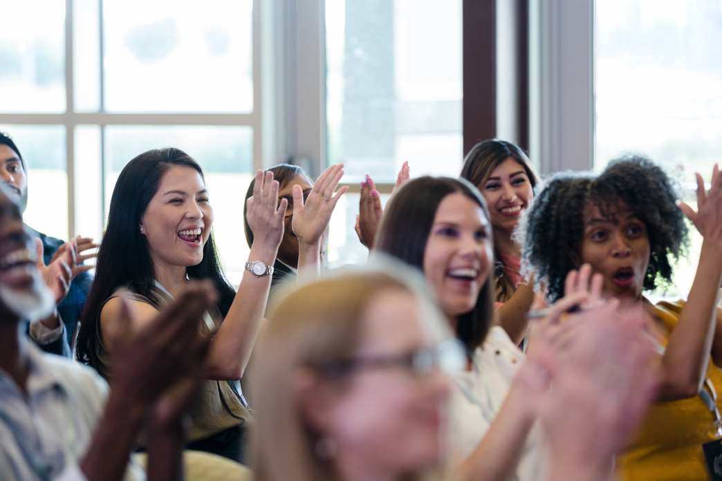 Diverse conference attendees cheer and laugh during expo session